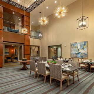 A modern dining room with high ceilings, elegant chandeliers, and contemporary artwork.