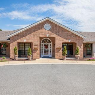 A symmetrical brick building with a central entrance and clear sky above.