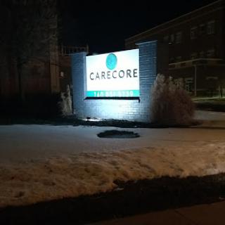 A illuminated business sign at night, partially surrounded by snow.