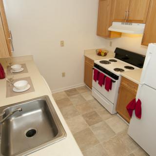Compact apartment kitchen with essential appliances and wooden cabinets.