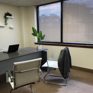 A modern office space featuring a desk, laptop, and comfortable seating.