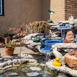 A garden fountain with cascading water, featuring a rubber duck and decorative elements.