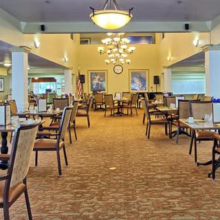A spacious and elegantly decorated dining area with tables, chairs, and chandeliers.