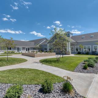 A well-maintained courtyard with pathways and landscaped gardens under a blue, cloud-dotted sky.