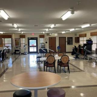 A spacious room with chairs and tables arranged neatly under fluorescent lighting.