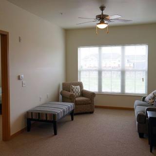 A cozy living room with a sofa, chair, and large window allowing natural light to fill the space.
