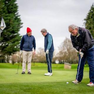 Three men enjoying a casual game of golf on a cloudy day.