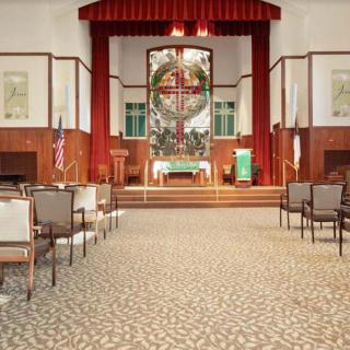 Interior view of a church with an altar and rows of chairs leading up to it.