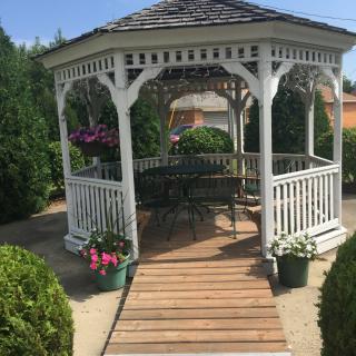 A charming white gazebo surrounded by lush greenery and vibrant flowers.
