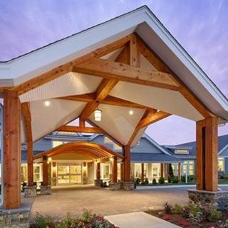 A modern building entrance with a wooden overhang and illuminated lights.