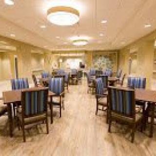 A modern dining room with neatly arranged tables and chairs, featuring warm lighting and a wooden floor.