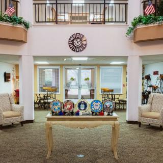 A welcoming lobby with comfortable seating, decorative plaques on a table, and lush plants.