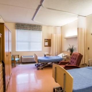 A hospital room with two beds and comfortable seating.