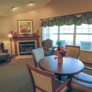 A cozy living room featuring a fireplace, dining table, and ample natural light.