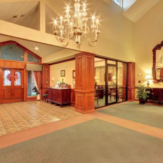 A spacious lobby with a chandelier, wood paneling, and a reception area.