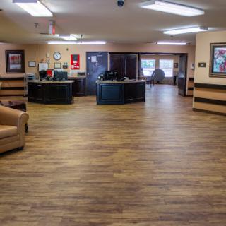 A spacious and well-lit lobby area featuring wooden flooring and comfortable seating.