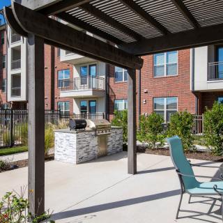 A modern apartment complex with an outdoor patio area featuring a pergola and seating.