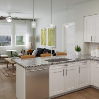 A modern open-concept kitchen with white cabinetry and granite countertops, connected to a cozy living room area.