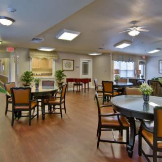 A cozy communal dining area with tables and chairs, decorated with plants and warm lighting.