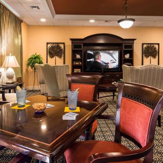 A cozy living room with a large table, chairs, and a television in the background.