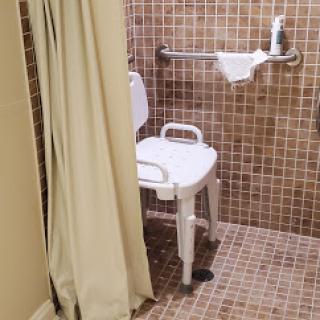 An accessible shower area equipped with a grab bar and a shower chair.