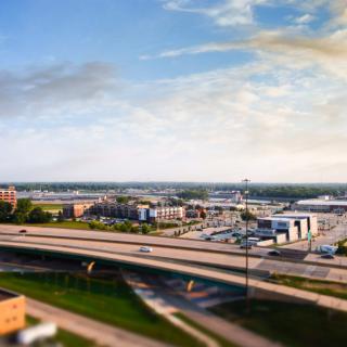 A cityscape featuring a highway with cars, surrounded by buildings under a partly cloudy sky.