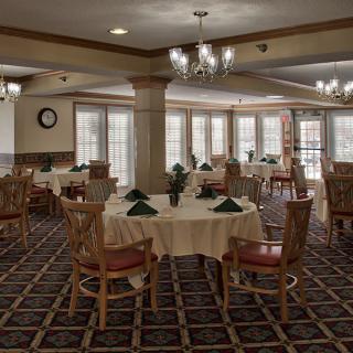 An elegantly arranged dining room with multiple tables set for a meal, featuring chandeliers and classic decor.