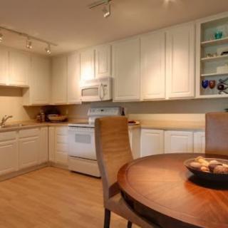A cozy kitchen featuring white cabinets, a dining table, and modern appliances.