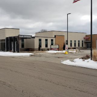 A modern educational building with snow on the ground under an overcast sky.