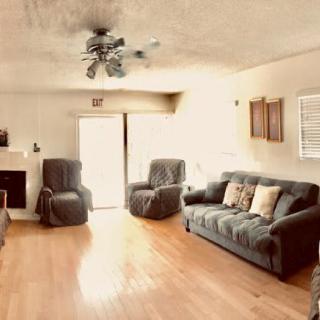 A cozy living room with a sofa, armchairs, and wood flooring.