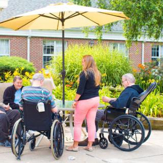 Seniors enjoying a sunny day outdoors while socializing with a caregiver.