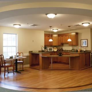 A modern kitchen and dining area featuring wooden cabinetry and flooring.