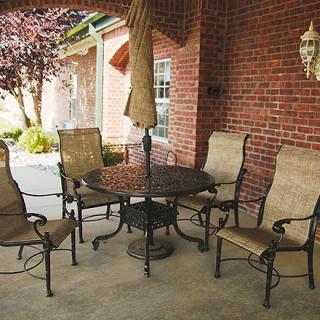 A cozy outdoor patio area with metal chairs, a table, and an umbrella, set against a brick wall.