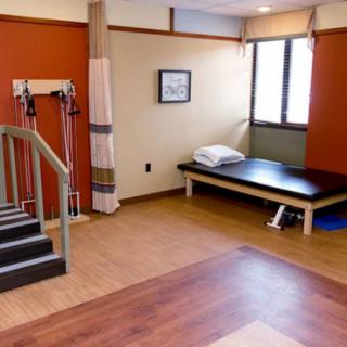 A physical therapy room equipped with exercise equipment and a treatment table.