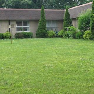 A neatly maintained lawn with shrubs and trees in front of a house.