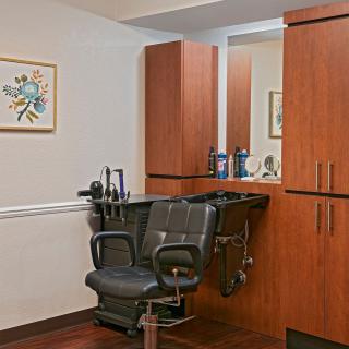 A clean and organized barber station with a mirror and wooden cabinets.