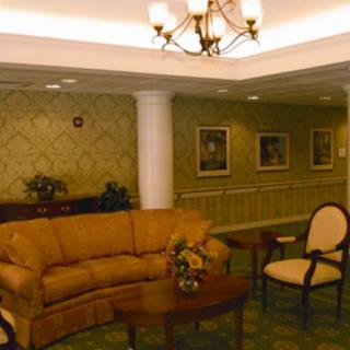 A cozy lobby area featuring a sofa, armchair, and coffee table under a chandelier.