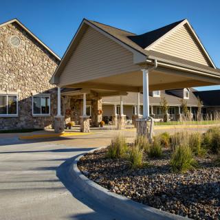A modern residential building with a stone facade and landscaped entrance.