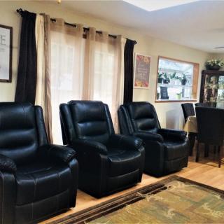 A cozy living room with black leather recliner chairs and a dining area.
