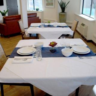 A neatly set dining table in a restaurant with white tablecloths and blue table runners.