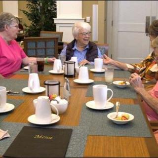 A group of elderly women sitting around a table, enjoying a meal together.