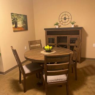 Cozy dining area with a round table and wooden chairs, complemented by a cabinet and wall decor.
