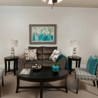 A cozy living room with a sofa, armchairs, and coordinating decor in teal and neutral tones.