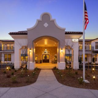 An illuminated building entrance with a flagpole at dusk.