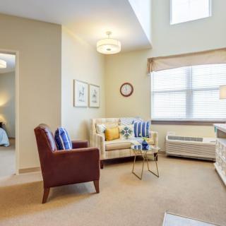 A cozy living room with a modern interior design, featuring a sofa, armchair, and coffee table.