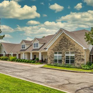 A suburban residential house with a stone facade under a cloudy sky.