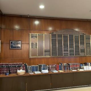 A polished wooden wall featuring a collection of books and name plaques, illuminated by soft lighting.
