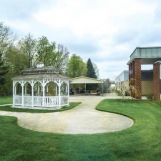 A charming outdoor scene featuring a gazebo surrounded by a manicured lawn and trees.
