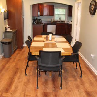 A modern dining area with a wooden table and chairs connected to a kitchen.