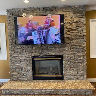 A cozy living room with a stone fireplace and a mounted TV.